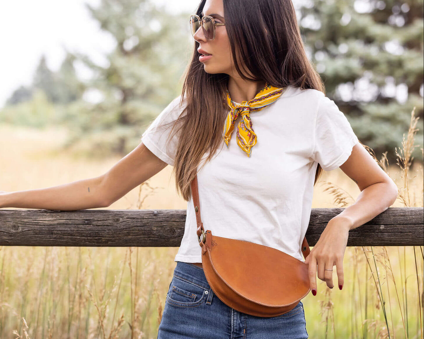 Woman standing outdoors with a wooden fence and natural background