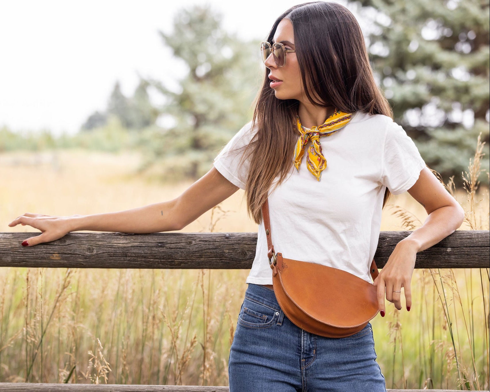 Woman standing outdoors with a wooden fence and natural background