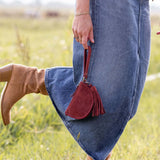 Person wearing blue jeans and brown boots with a red bag in a grassy field