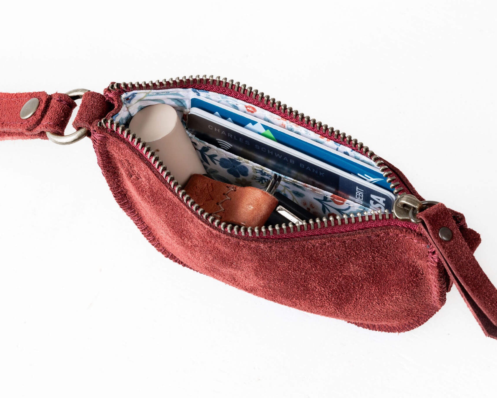 Red crossbody bag with a zipper open, showing its interior.