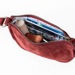 Red crossbody bag with a zipper open, showing its interior.