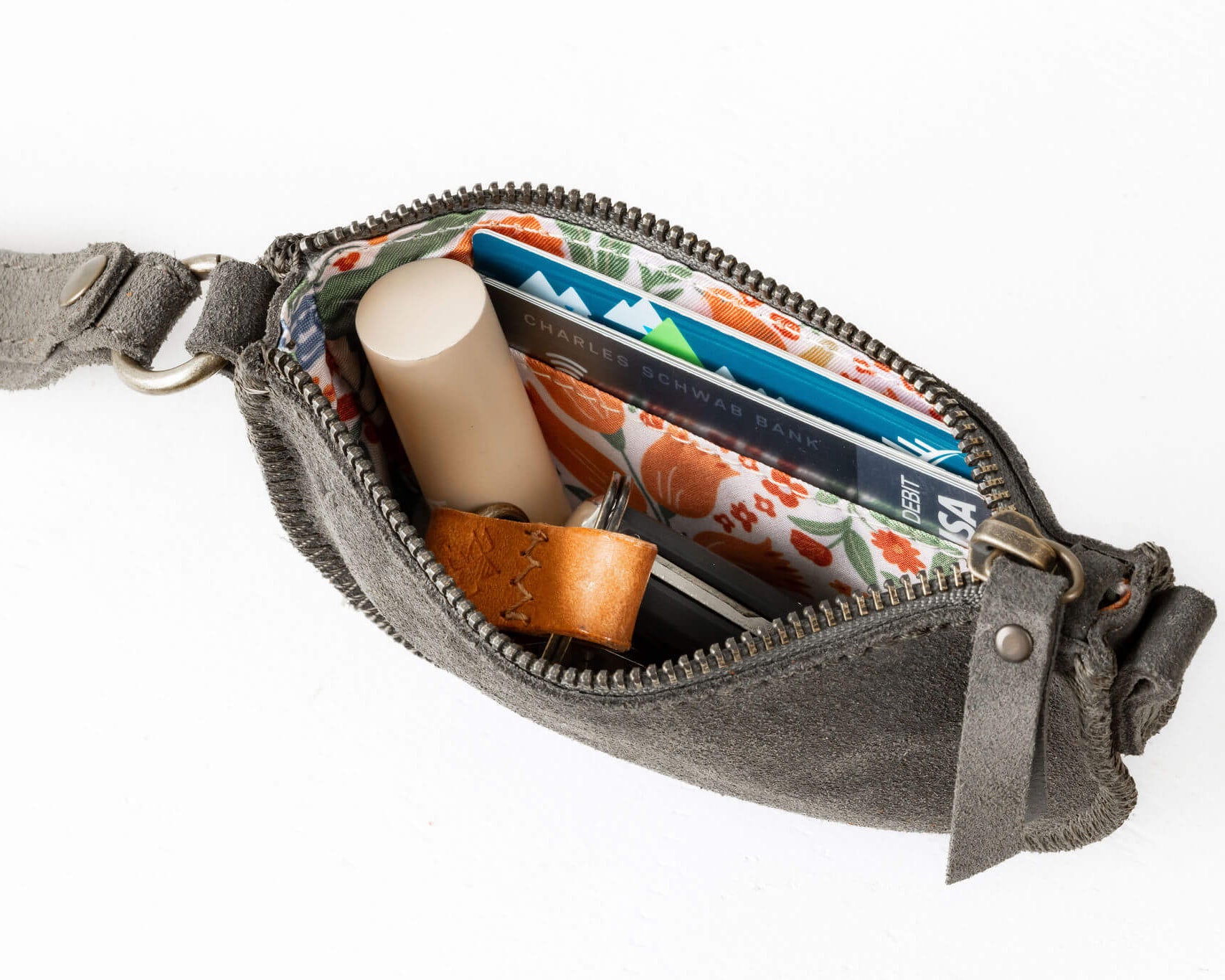 Gray waist bag with items including a candle, cards, and a small container on a white background