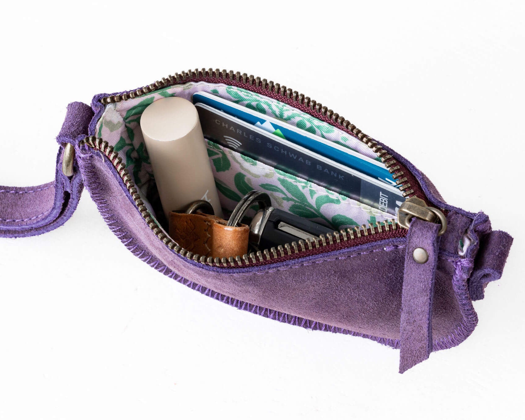Purple crossbody bag with items inside on a white background