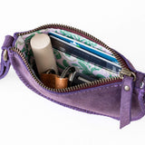Purple crossbody bag with items inside on a white background