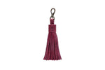 Maroon tassel keychain on a white textured background