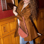 Woman in a brown coat using a vintage payphone in an ornate room.