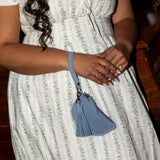 Woman in a white dress with a blue purse, standing indoors.