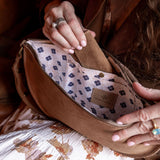 Close-up of a brown leather bag with a patterned interior, held by a person.