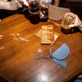 Two people enjoying drinks at a wooden table with board games and a small bag.