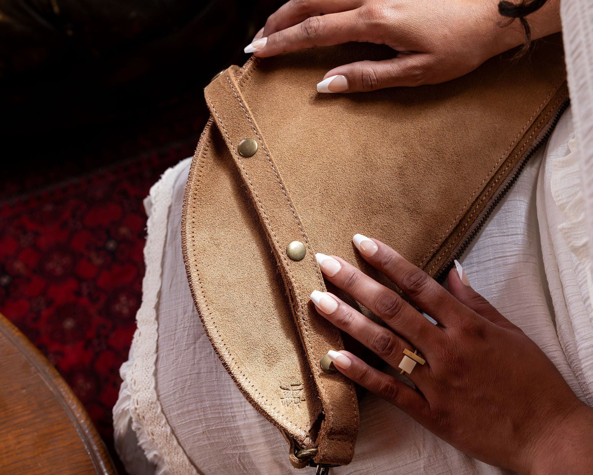 Person holding a brown leather clutch bag with a blurred indoor background