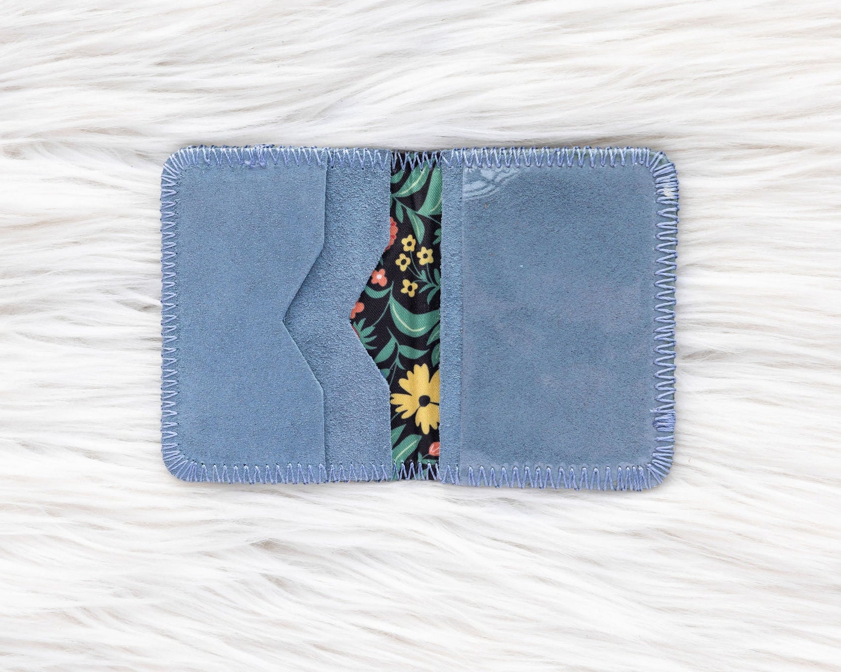 Blue fabric cardholder with floral design on a white textured background