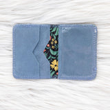 Blue fabric cardholder with floral design on a white textured background