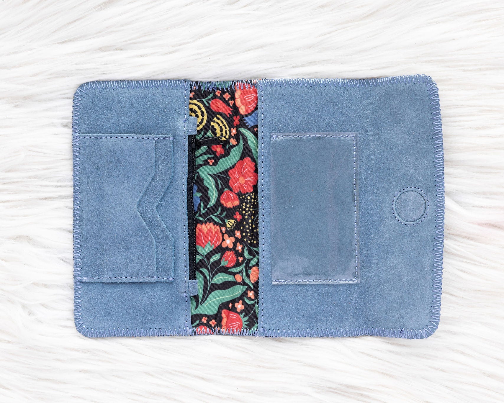 Blue fabric wallet with floral interior lining on a white background