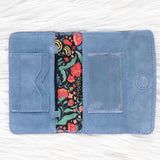 Blue fabric wallet with floral interior lining on a white background