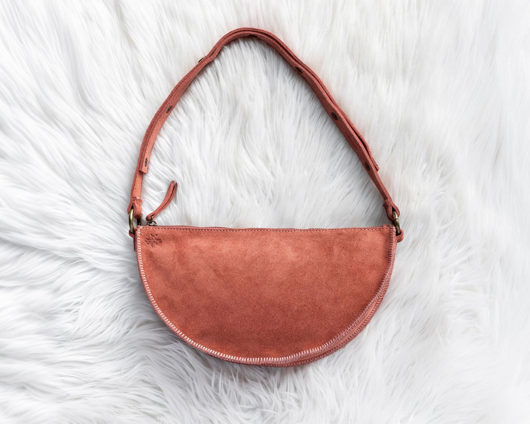 Mauve leather handbag on a white fur surface