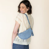 Woman carrying a blue crossbody bag against a beige background