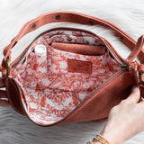 Person opening a pink handbag with floral interior on a white surface