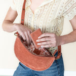 Person holding a brown leather bag with a white background