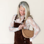 Woman holding a beige handbag against a plain background