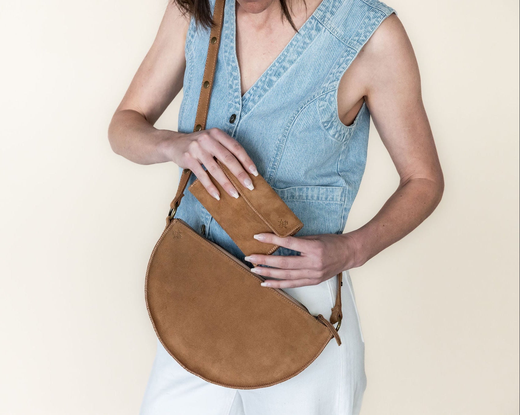 Woman holding a brown leather bag against a plain background