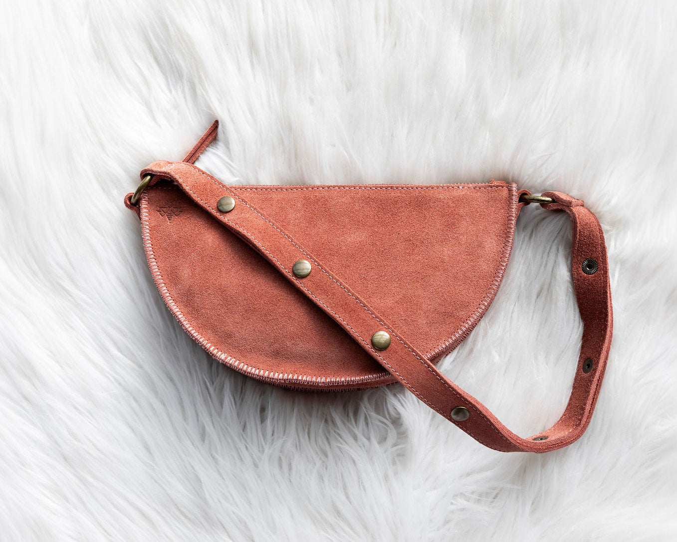 Mauve leather saddle bag on a white fur surface