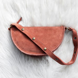 Mauve leather saddle bag on a white fur surface