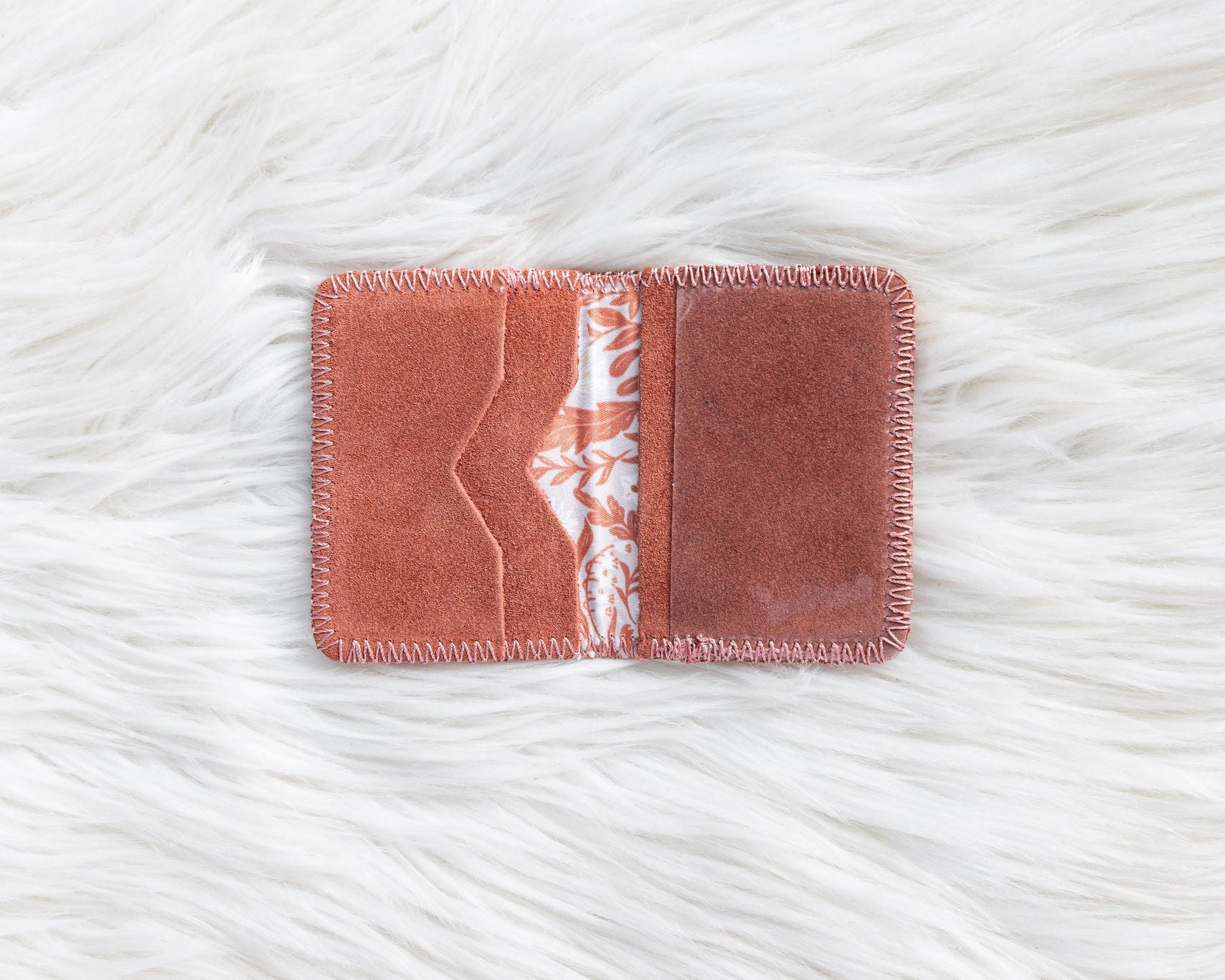 Rectangular pink fabric patch with a white floral pattern on a textured white surface