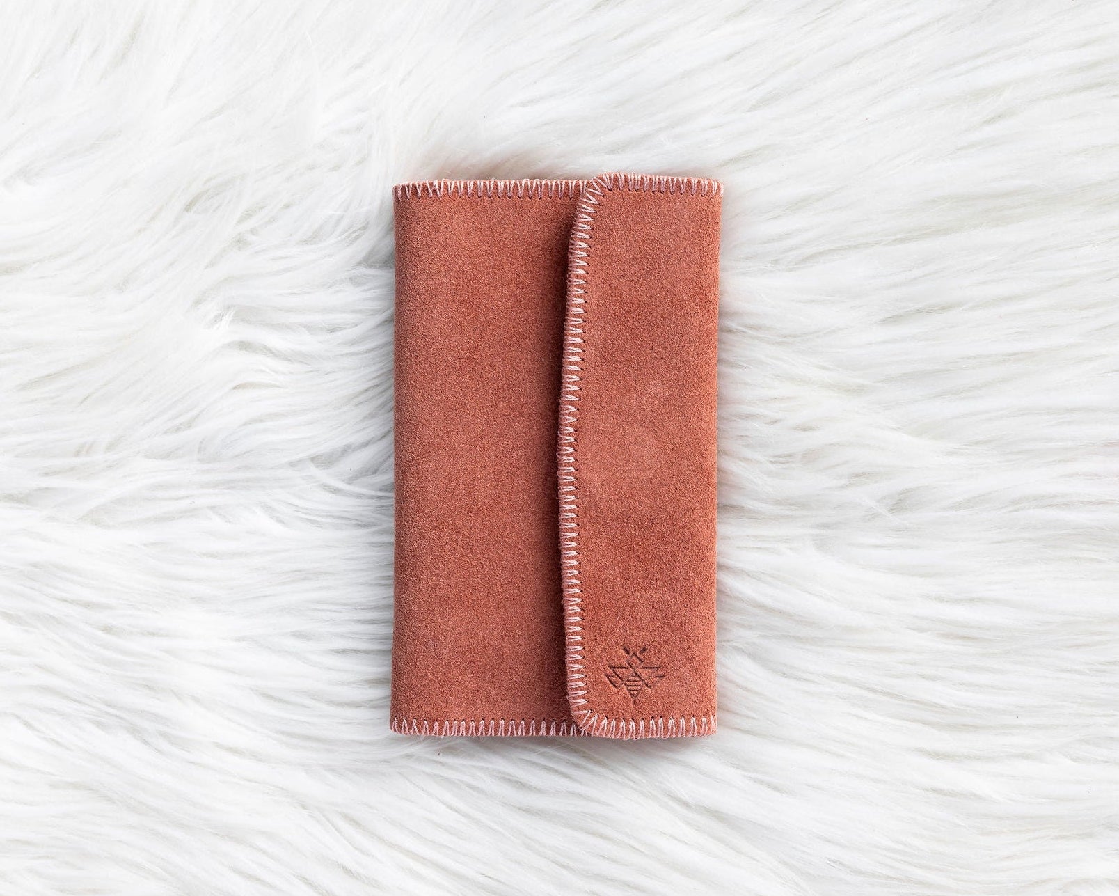 Folded pink blanket on a textured white surface