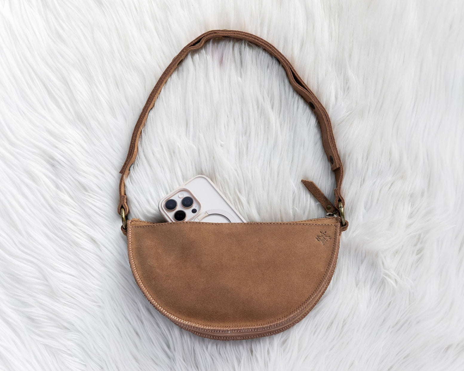 Brown leather crossbody bag on a white textured surface