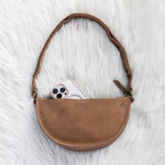 Brown leather crossbody bag on a white textured surface
