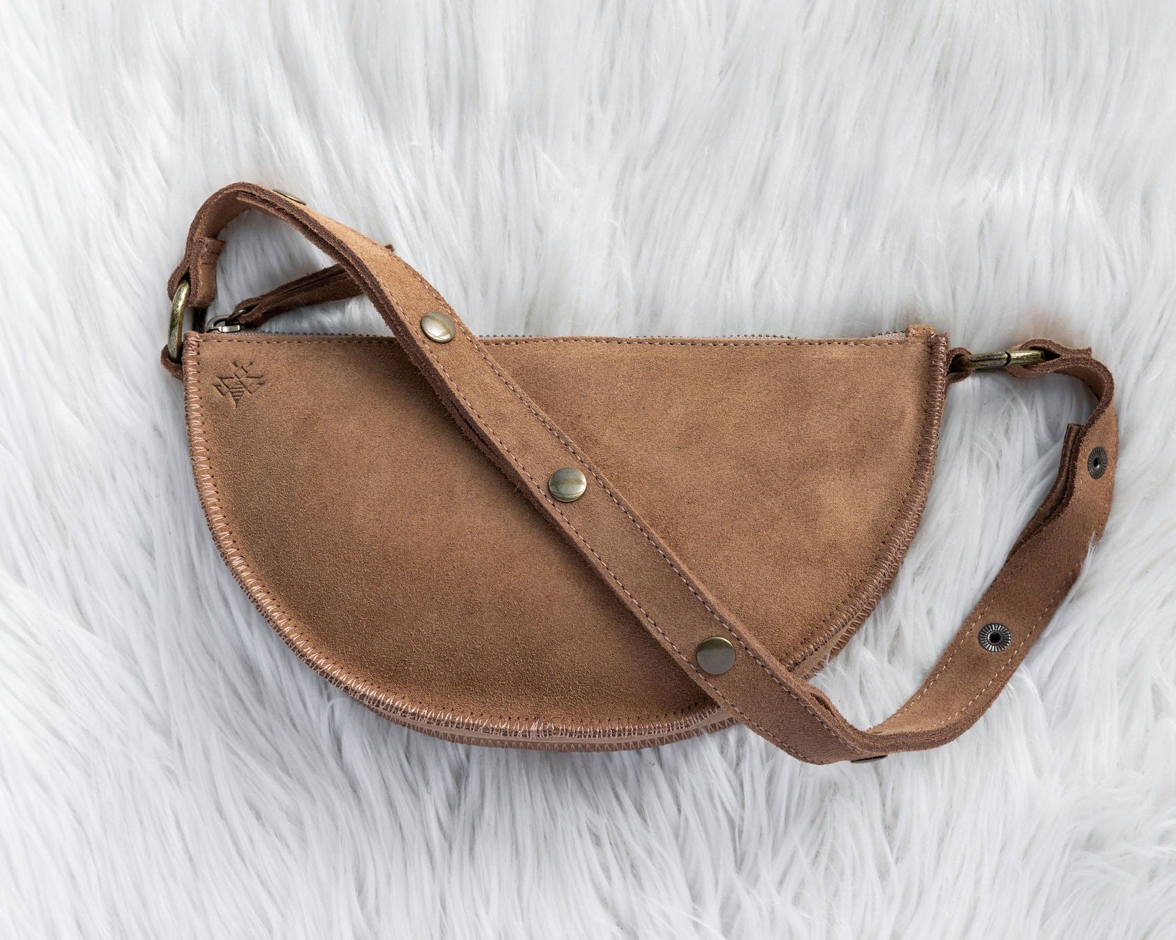 Brown leather bag with gold hardware on a white fur background