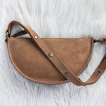 Brown leather bag with gold hardware on a white fur background