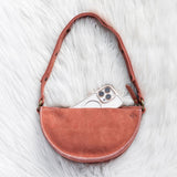 Mauve leather bag with a phone inside on a white fur surface