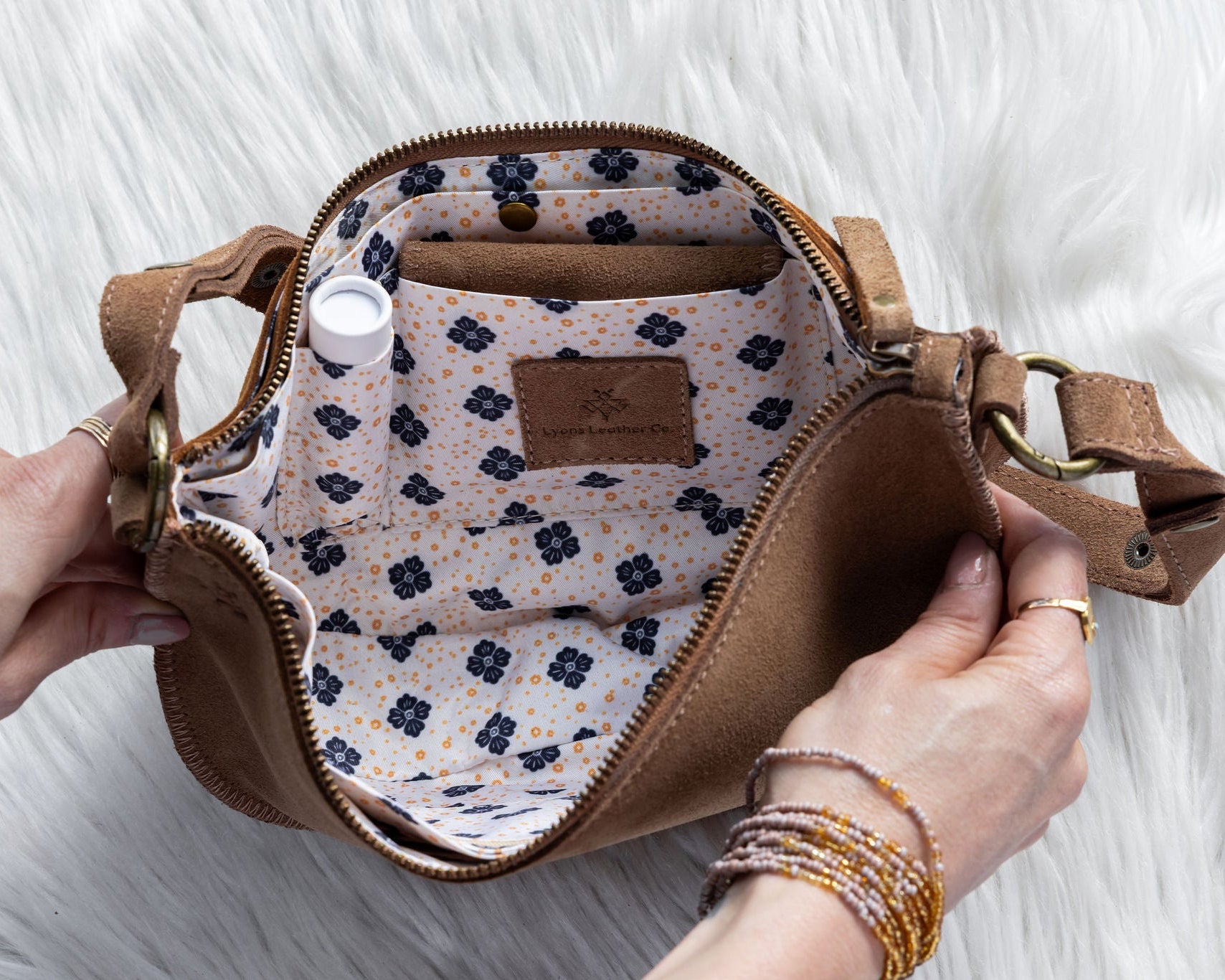 Brown handbag with floral interior on a white fluffy surface