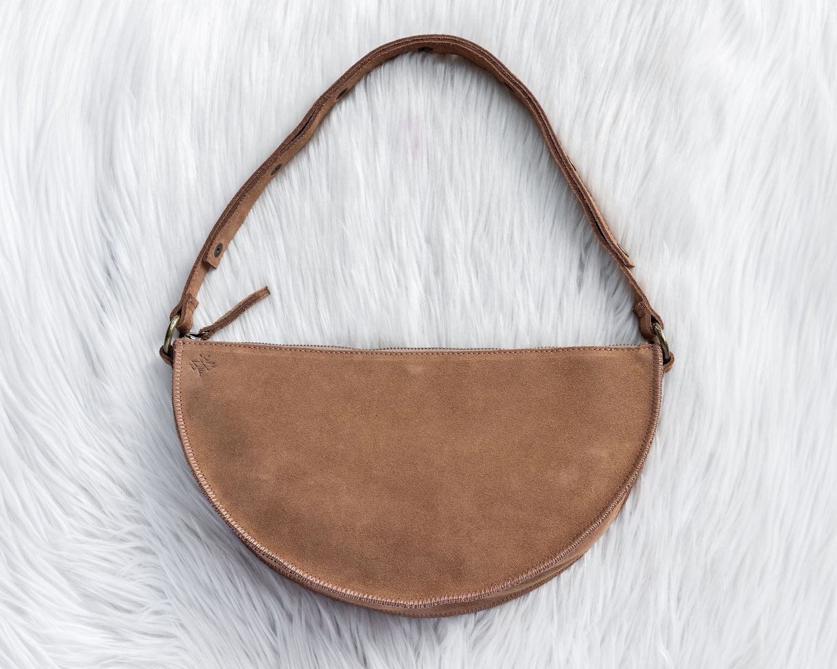 Brown suede handbag on a white fur surface