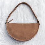 Brown suede handbag on a white fur surface
