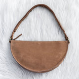 Brown suede handbag on a white fur surface