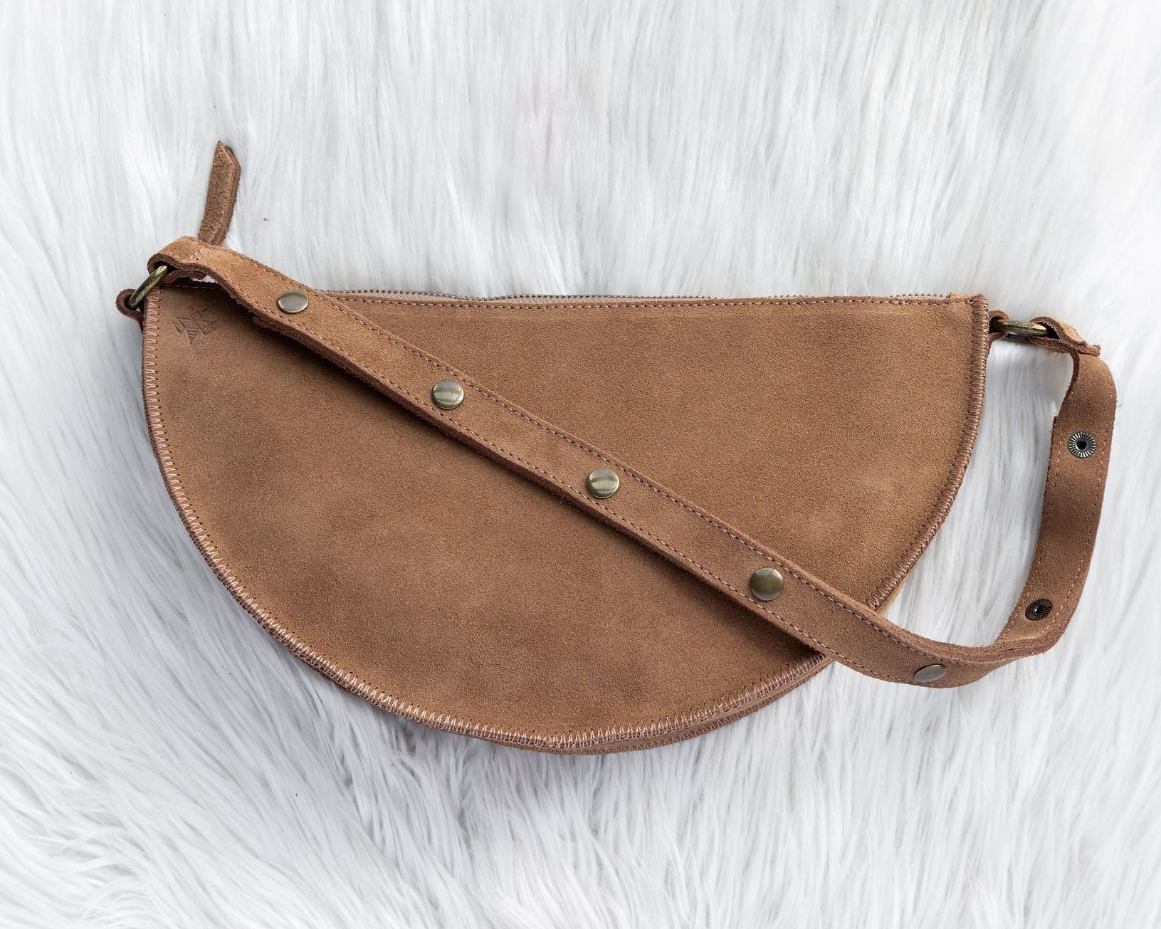 Brown leather saddle bag on a textured white surface