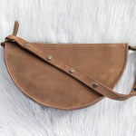 Brown leather saddle bag on a textured white surface
