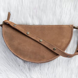 Brown leather saddle bag on a textured white surface
