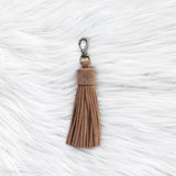 Brown tassel keychain on a textured white background