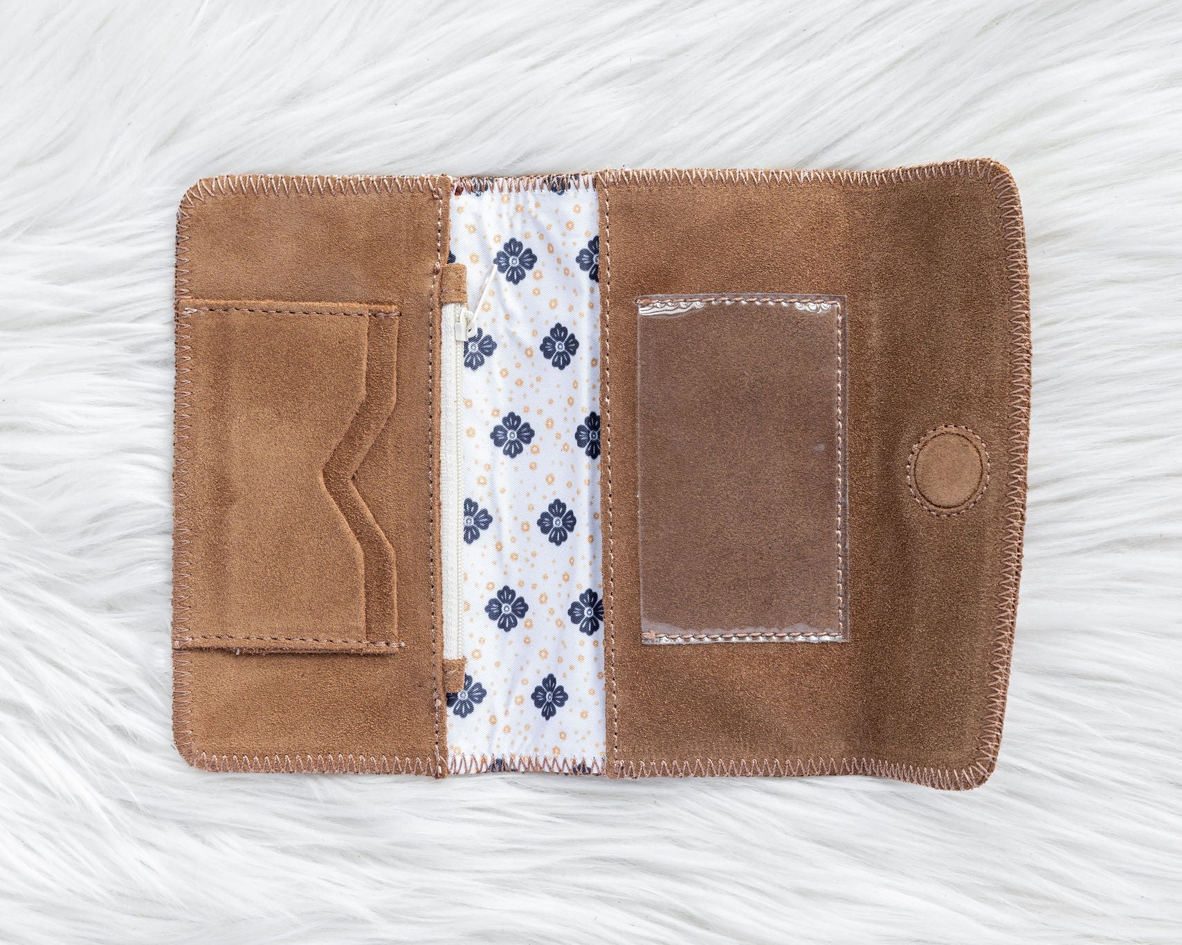 Brown leather wallet with floral lining on a white textured background