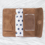 Brown leather wallet with floral lining on a white textured background
