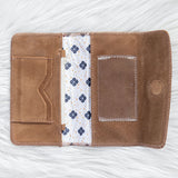 Brown leather wallet with floral lining on a white textured background