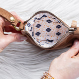 Person holding a small brown leather pouch with floral interior on a white background