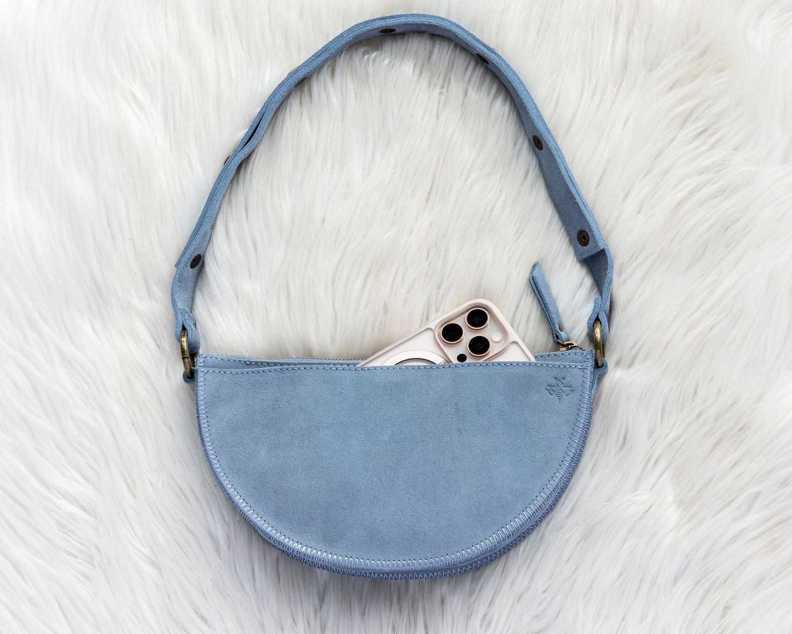 Blue handbag with a phone inside on a white fur surface