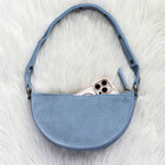 Blue handbag with a phone inside on a white fur surface
