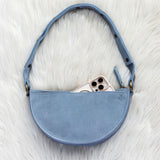 Blue handbag with a phone inside on a white fur surface