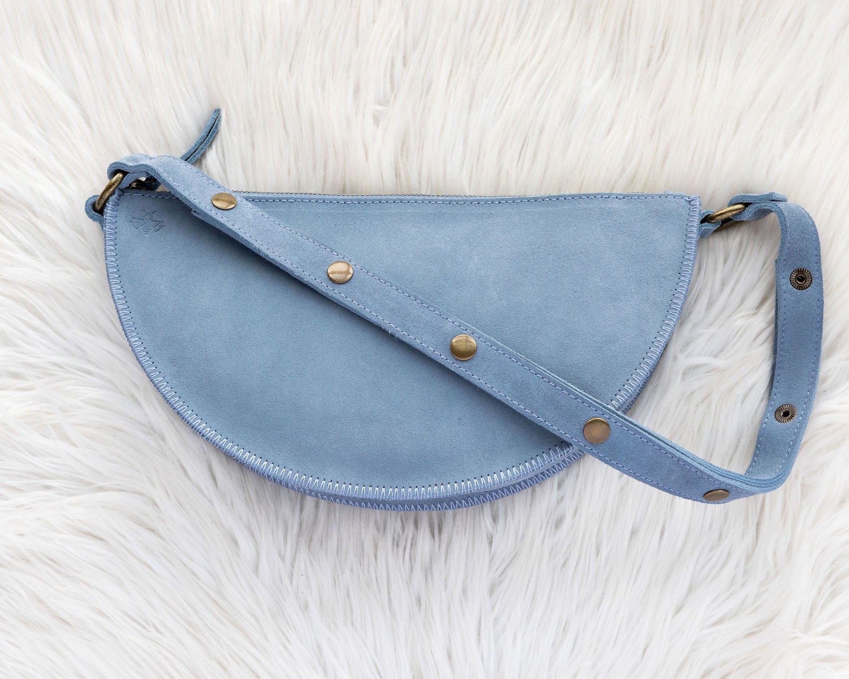 Blue leather waist bag on a white fur surface