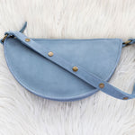 Blue leather waist bag on a white fur surface